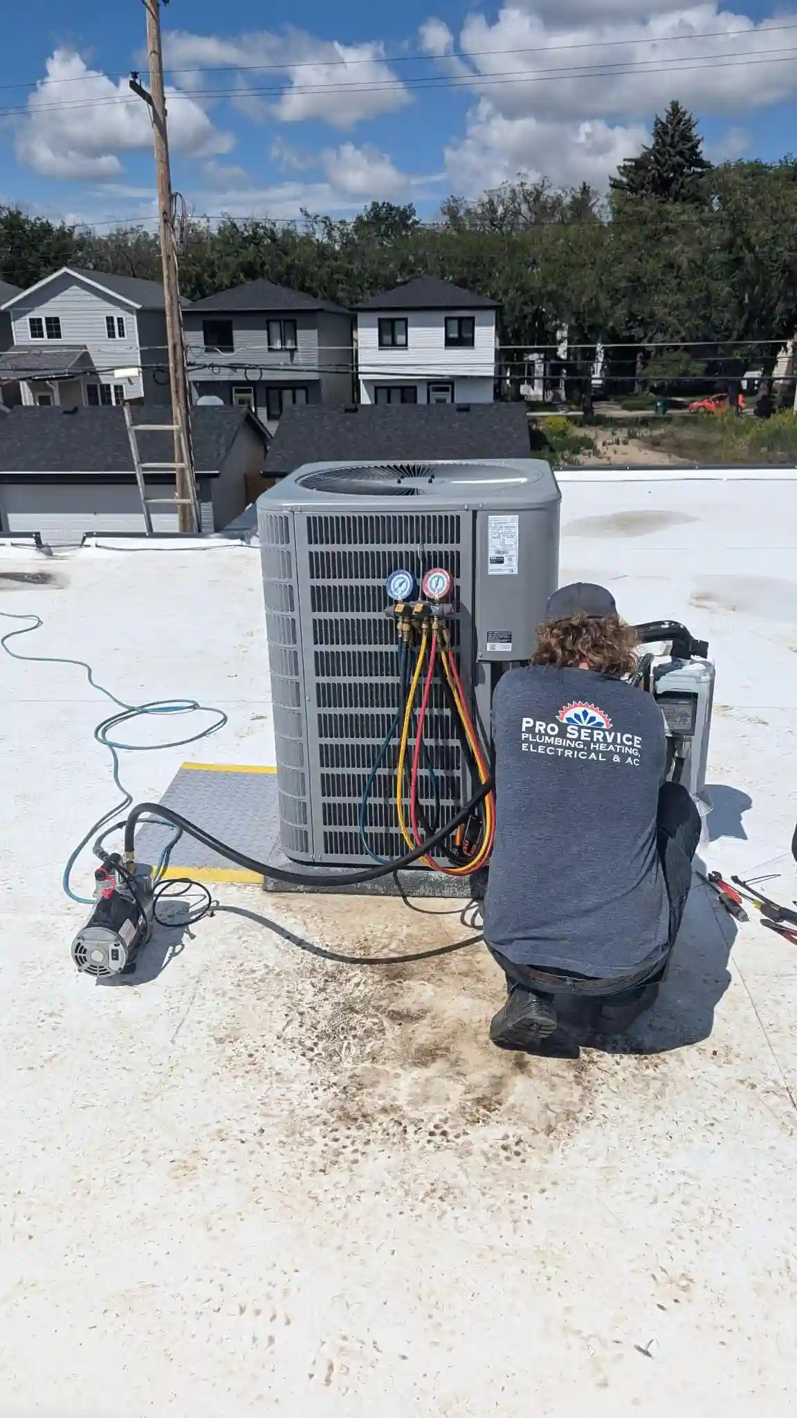 Rooftop AC Installation by Pro Service Mechanical Pro Service Mechanical technician charging rooftop AC unit with vacuum pump and refrigerant gauges in Saskatoon